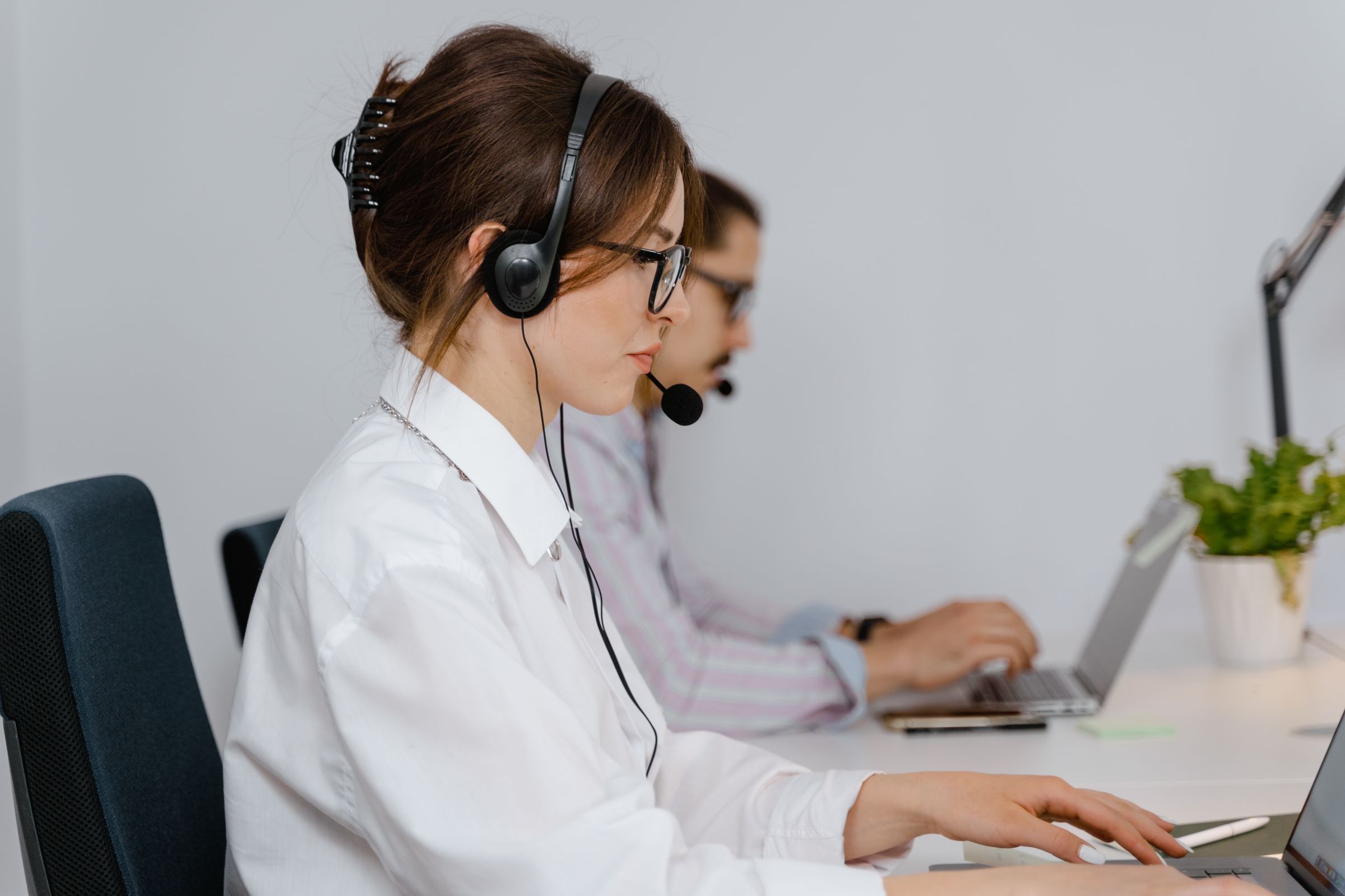 A support agent with a headset typing at her desk