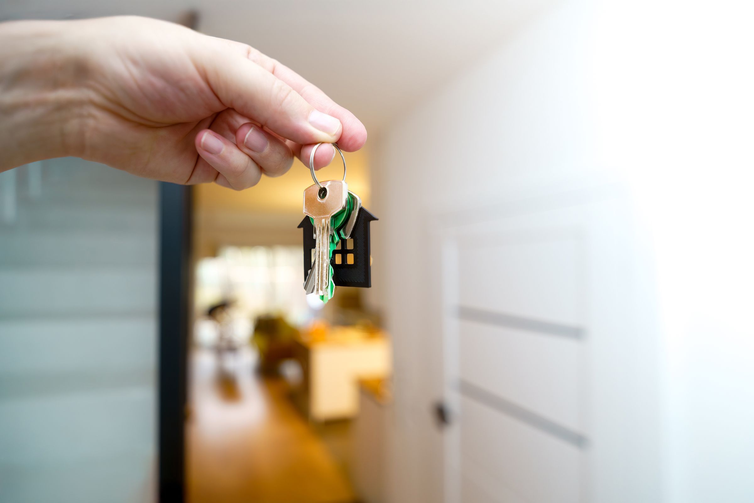 A hand holding house keys in a bright modern apartment