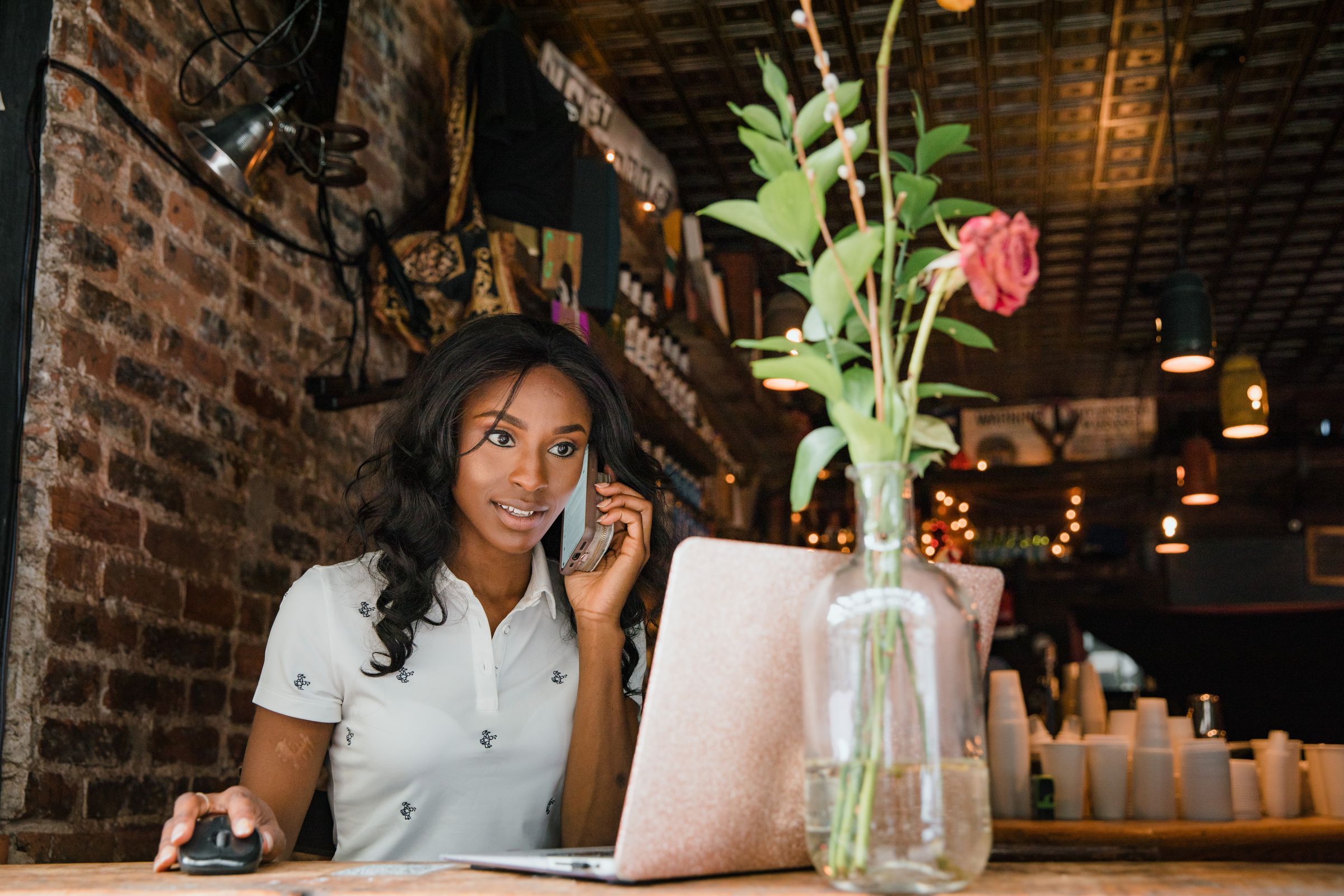 A woman on a phone call at her laptop in a café