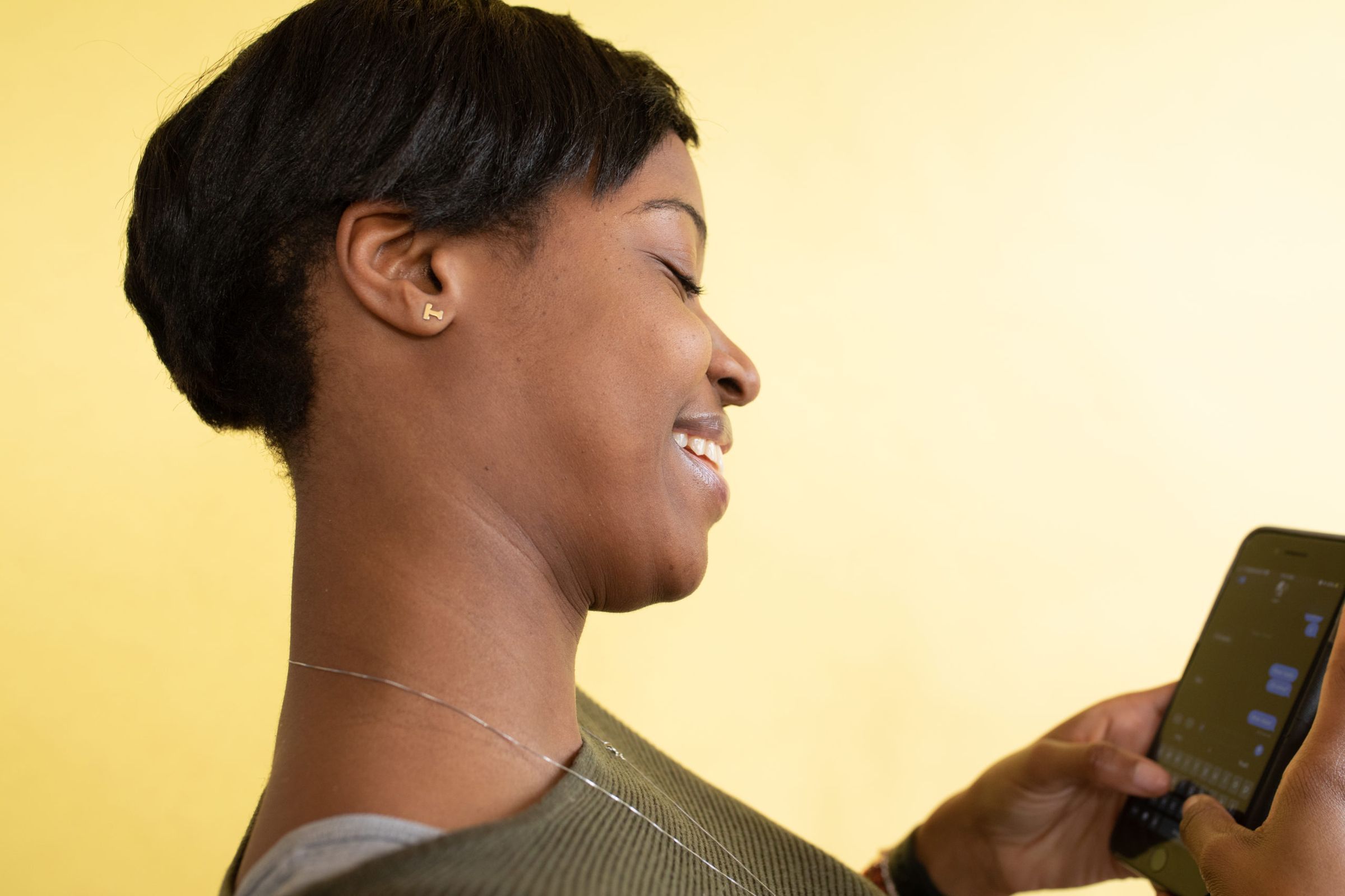 A woman smiling as she types on her phone