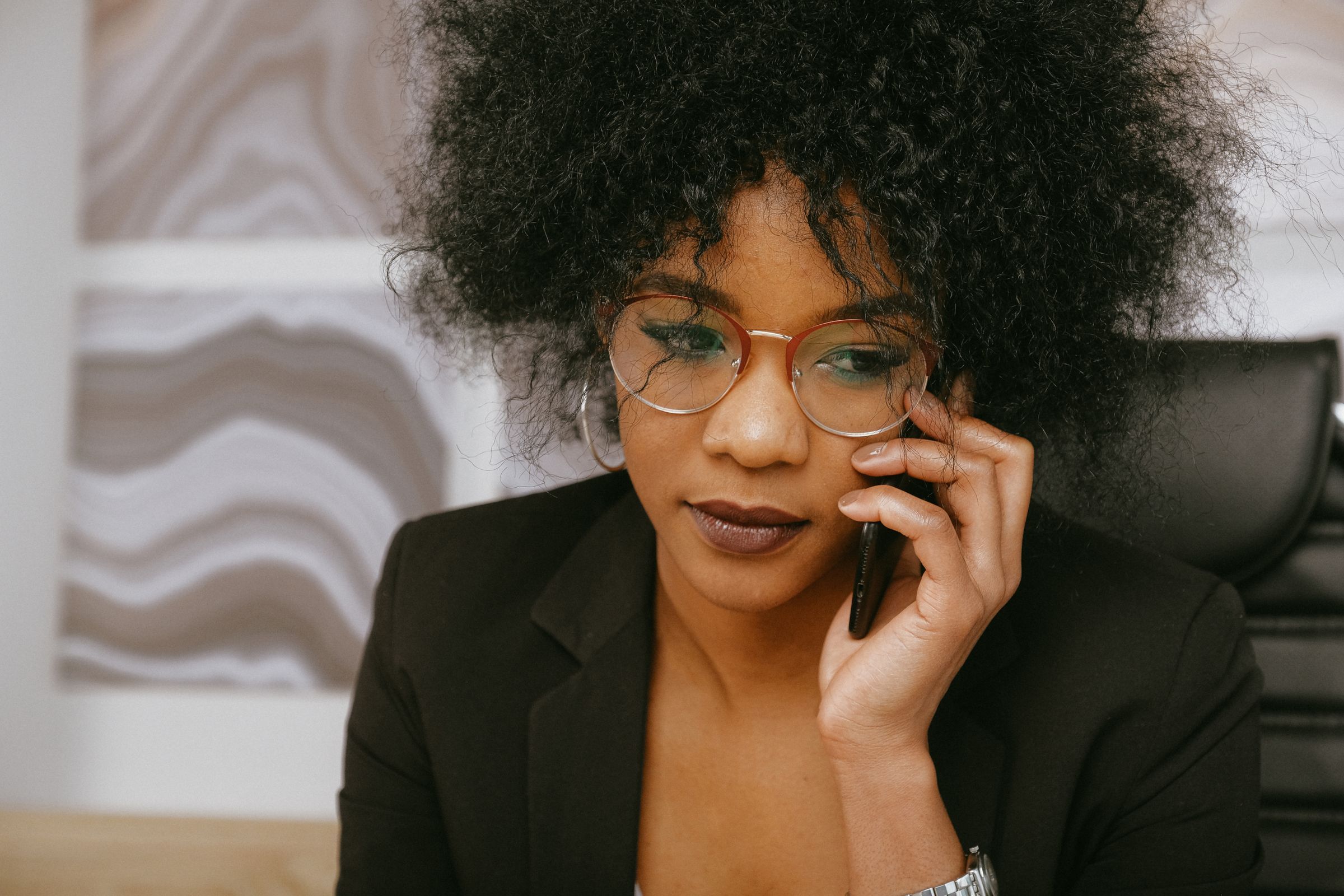 A woman in glasses listening closely on a phone call