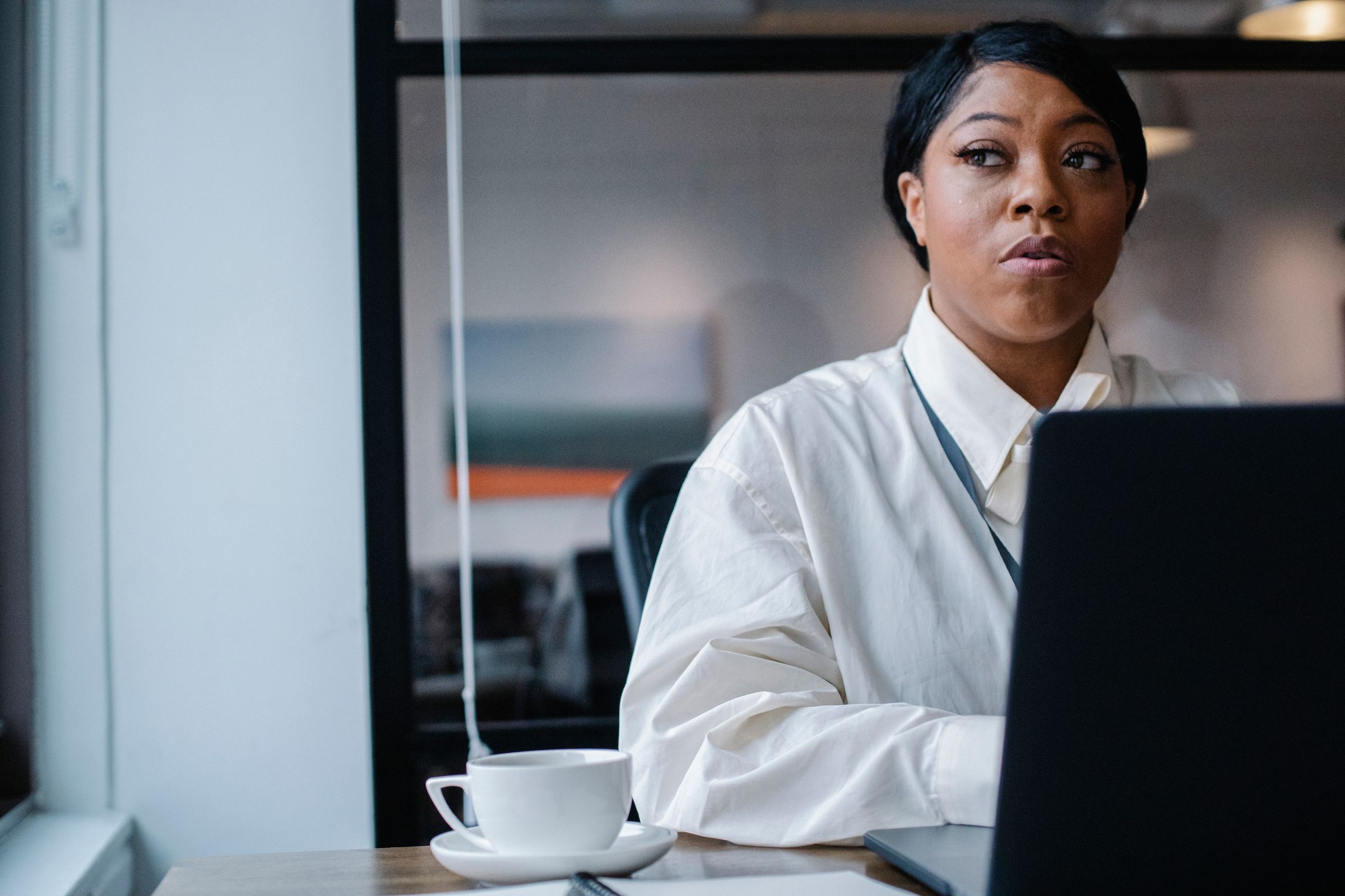 A woman thinking at her laptop in an office