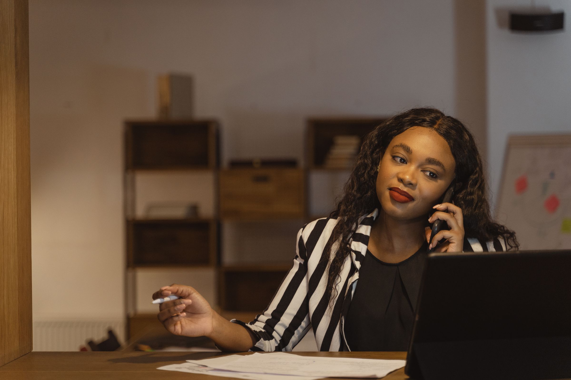 A woman on a phone call at her desk in a home office